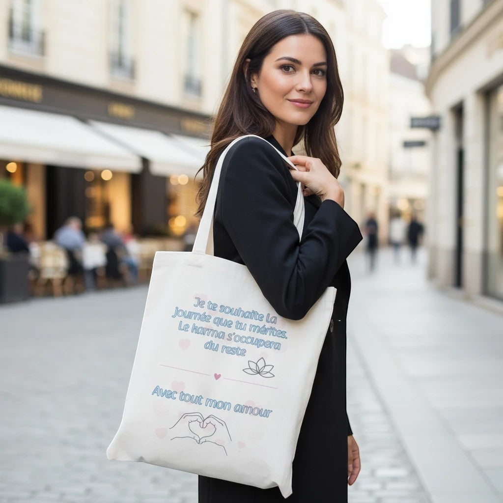 L'Atelier de Lylou Sac fourre-tout blanc en coton avec inscription humoristique "Je te souhaite la journée que tu mérites. Le karma s'occupera du reste. Avec tout mon amour" et motif de mains formant un cœur.