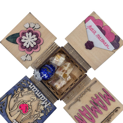 Boîte cadeau surprise en bois L'Atelier de Lylou pour la Fête des Mères, décorée de fleurs et de cœurs, contenant des chocolats et des friandises.