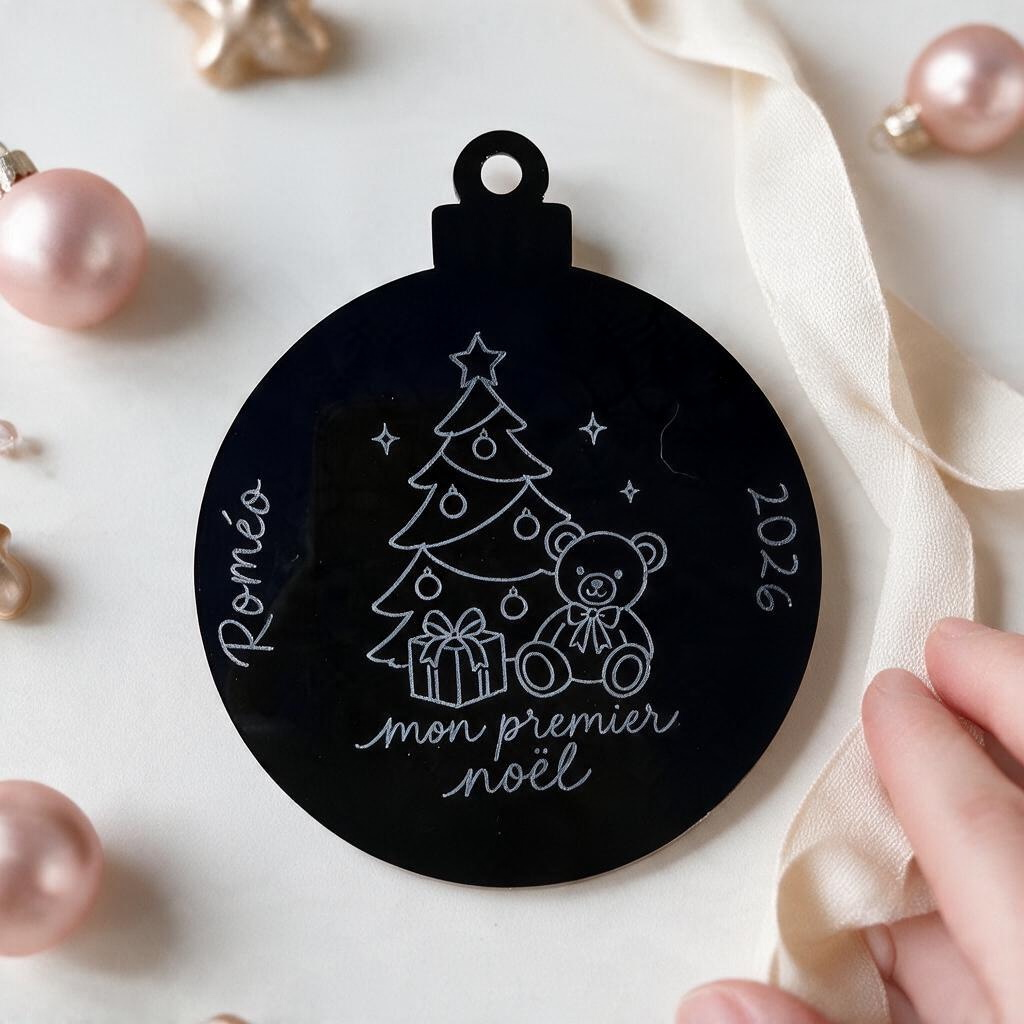 Boule de Noël L'Atelier de Lylou en acrylique noir gravée avec un ourson, un sapin et l'inscription Mon premier Noël