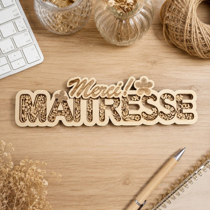 Décoration en bois multicouches "Merci Maitresse" de L'Atelier de Lylou, avec gravure florale et texte en relief.