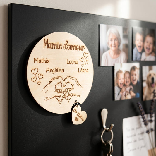 Magnet rond en bois personnalisé "Mamie d'amour" avec prénoms, mains en cœur et petit cœur "On t'aime". L'Atelier de Lylou.