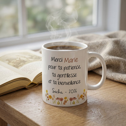 Mug blanc L'Atelier de Lylou personnalisé "Merci Marie pour ta patience, ta gentillesse et ta bienveillance Sacha - 2026" avec un motif floral coloré.
