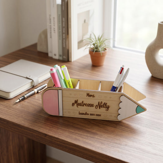 Organiseur de bureau en bois L'Atelier de Lylou en forme de crayon, personnalisé avec "Maîtresse Nelly" et "Leandro 2015-2026". Rose, blanc et vert.