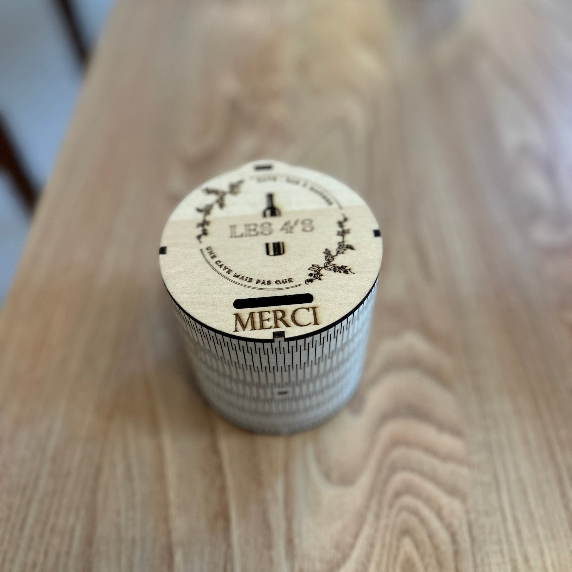 Tirelire ronde en bois L'Atelier de Lylou personnalisée avec "LES 4/3" et "MERCI", gravure laser.