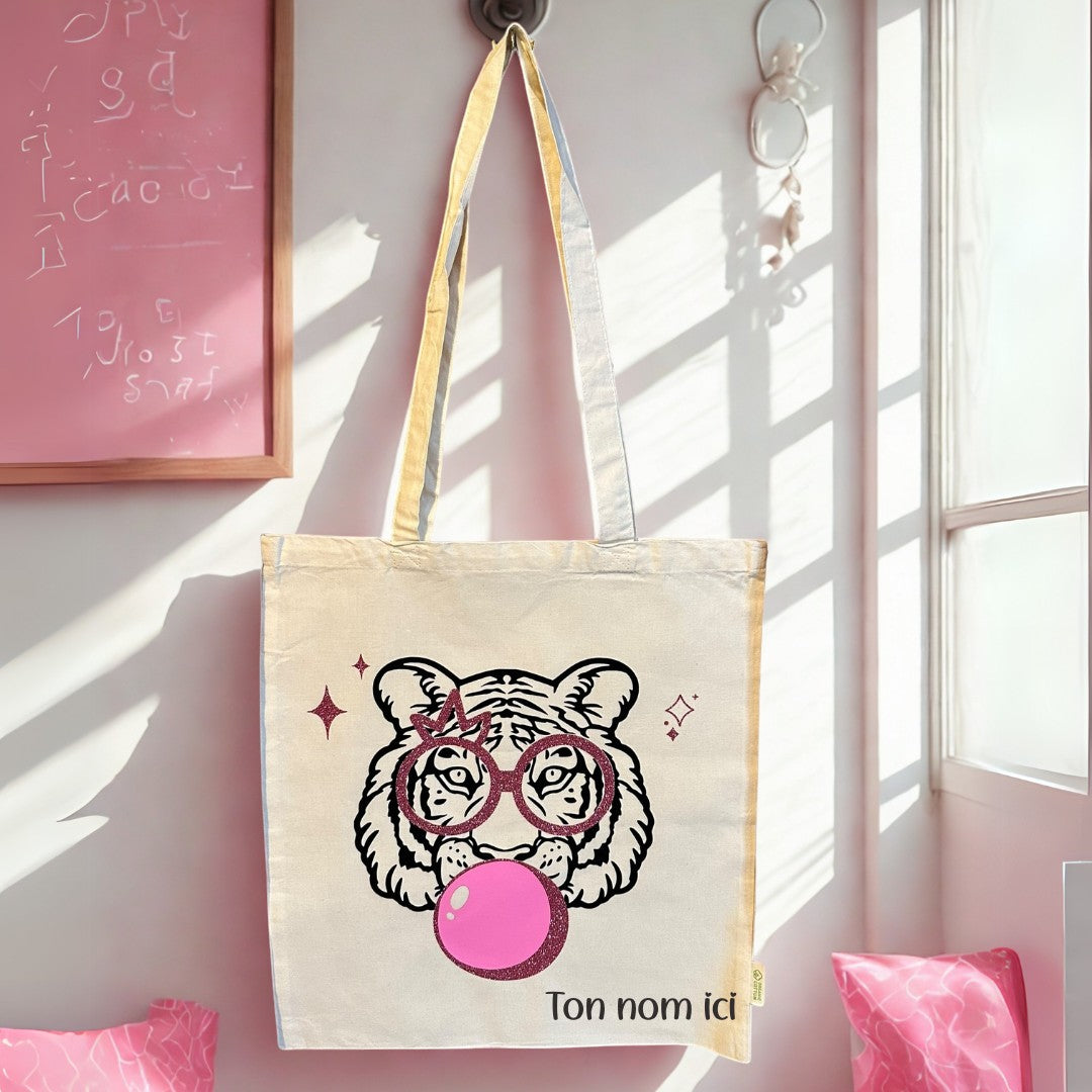 Tote bag blanc en coton L'Atelier de Lylou avec un tigre stylisé portant des lunettes et mâchant une bulle de chewing-gum rose.