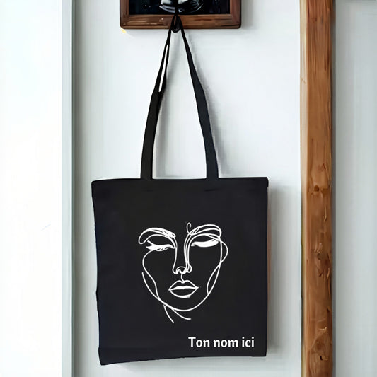 L'Atelier de Lylou tote bag noir en coton avec un dessin de visage abstrait et personnalisable
